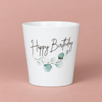 White Happy Birthday ceramic pot with green botanical decoration, handwritten-style lettering and a gently tapered shape