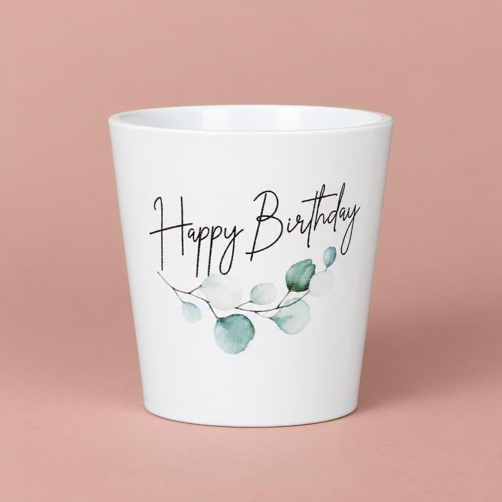 White Happy Birthday ceramic pot with green botanical decoration, handwritten-style lettering and a gently tapered shape